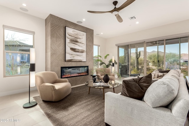 tiled living room featuring a fireplace and ceiling fan