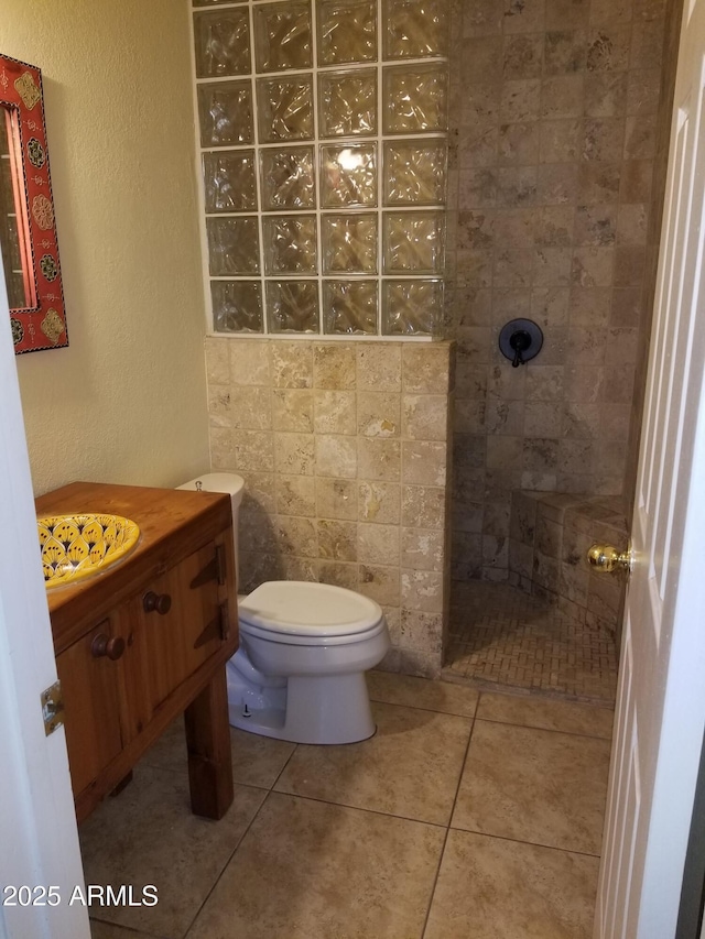 bathroom featuring tiled shower, tile patterned floors, toilet, and vanity