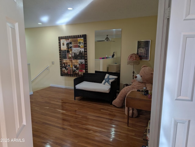 living area featuring dark wood-type flooring and ceiling fan