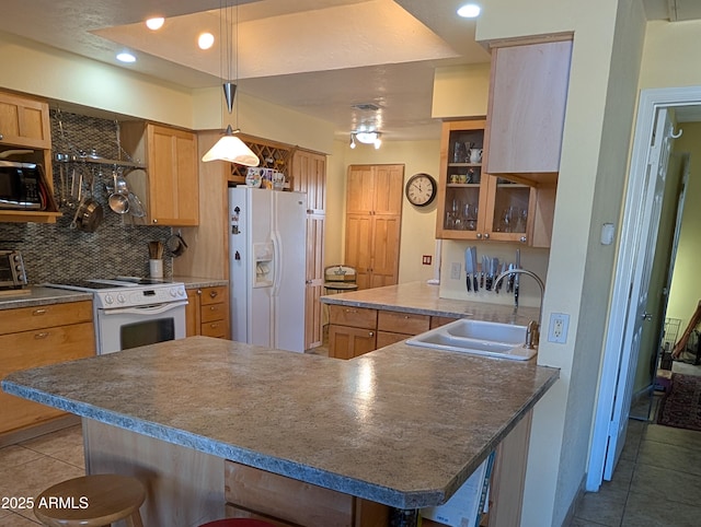 kitchen featuring a breakfast bar, decorative light fixtures, sink, backsplash, and white appliances