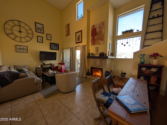 living room with a tiled fireplace, light tile patterned floors, and a towering ceiling