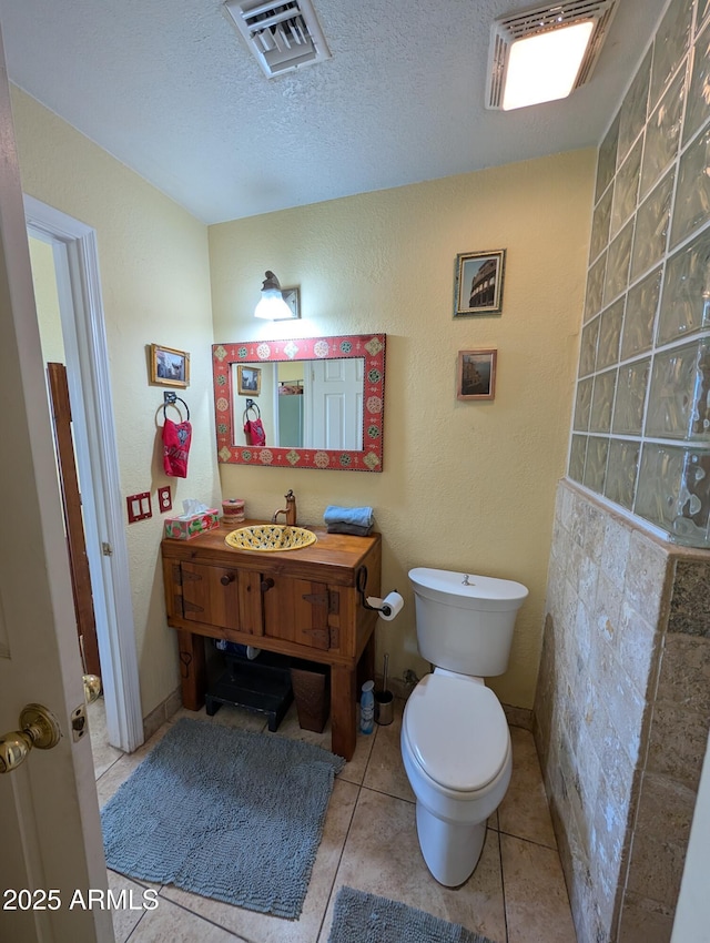 bathroom with tile patterned floors, vanity, toilet, and a textured ceiling