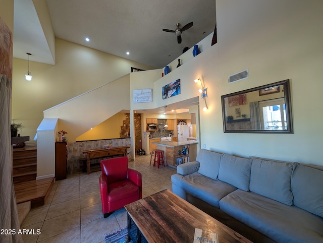 tiled living room featuring ceiling fan and a high ceiling