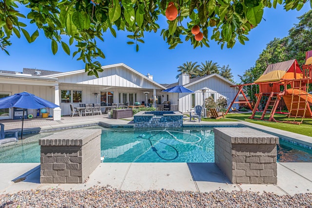 view of swimming pool featuring a patio area, a pool with connected hot tub, and a playground