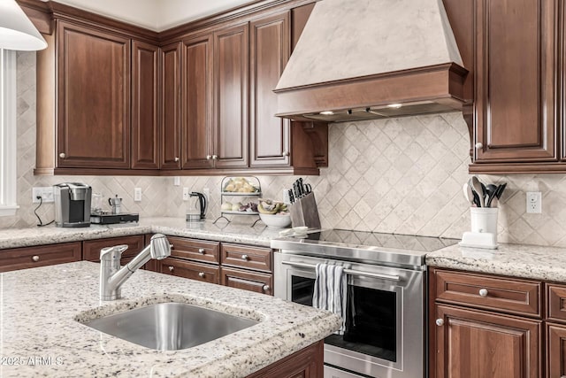 kitchen with a sink, custom range hood, backsplash, and electric range