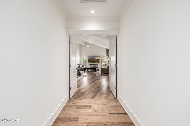 hallway with baseboards, recessed lighting, light wood-style flooring, crown molding, and lofted ceiling