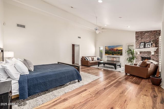 bedroom featuring high vaulted ceiling, a fireplace, visible vents, recessed lighting, and wood finished floors