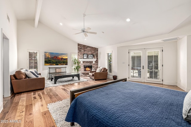 bedroom with light wood-style floors, access to exterior, beamed ceiling, and a brick fireplace