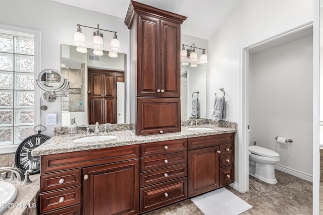 bathroom featuring double vanity, vaulted ceiling, a sink, and toilet
