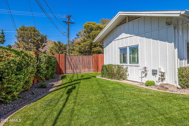 view of side of home with board and batten siding, fence, and a lawn