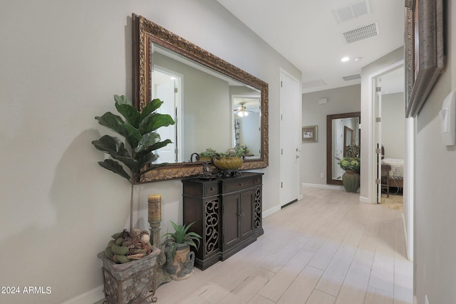 hallway with light wood-style flooring, visible vents, and baseboards