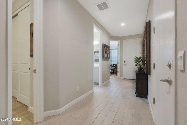 corridor featuring baseboards, visible vents, and light wood-style floors