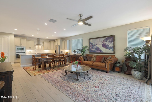 living room featuring light wood-style flooring, visible vents, a ceiling fan, and recessed lighting