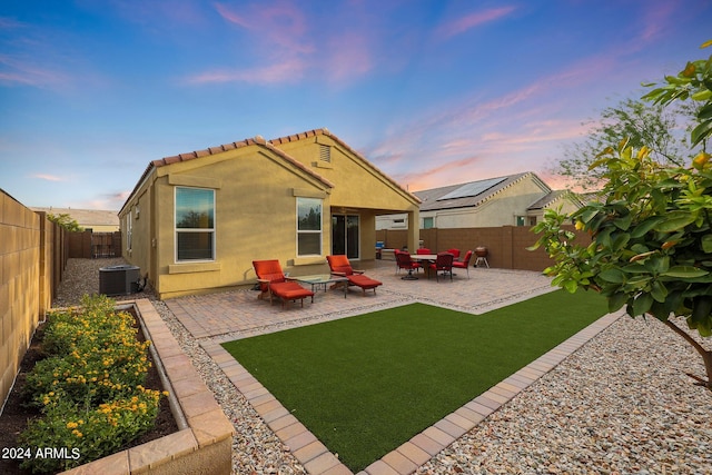 rear view of property with a patio, a tile roof, a fenced backyard, central AC, and stucco siding