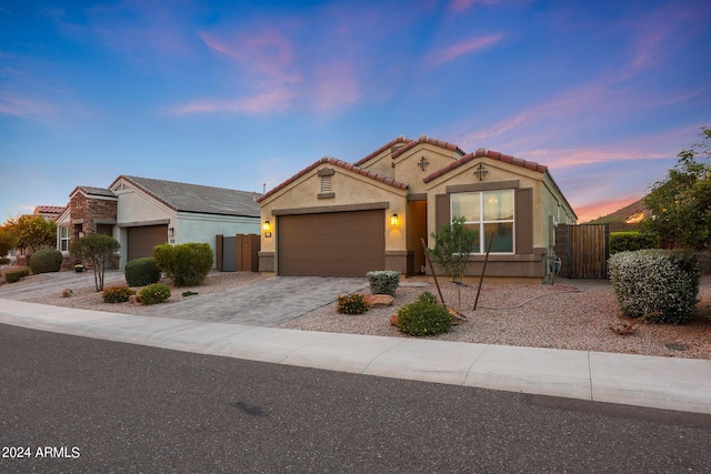 view of front of house with decorative driveway, stucco siding, a gate, a garage, and a tiled roof