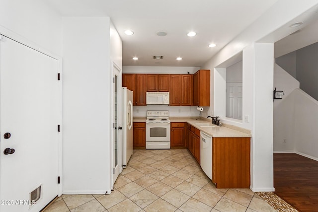 kitchen featuring sink, light tile patterned flooring, and white appliances