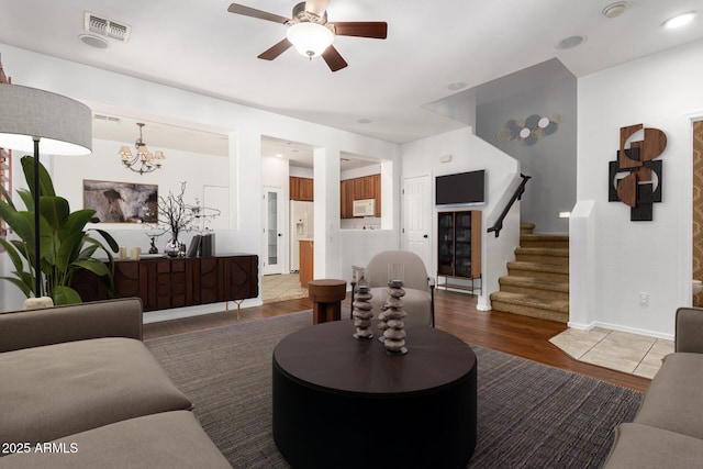 living room with dark hardwood / wood-style floors and ceiling fan with notable chandelier