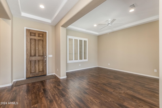 entrance foyer with a tray ceiling, ceiling fan, and dark wood-type flooring