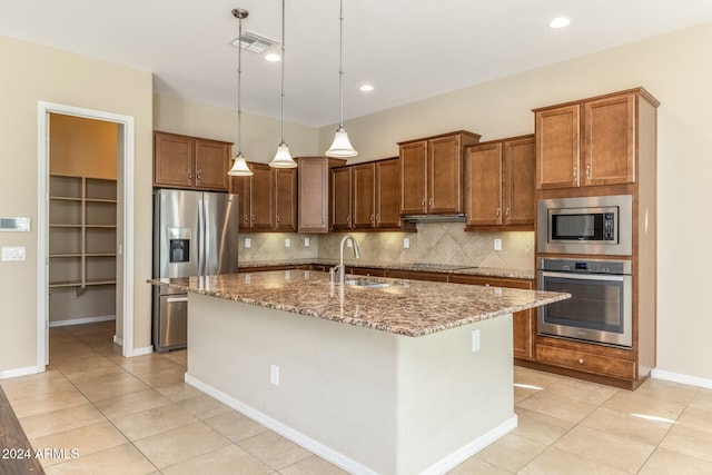 kitchen featuring pendant lighting, sink, decorative backsplash, an island with sink, and stainless steel appliances