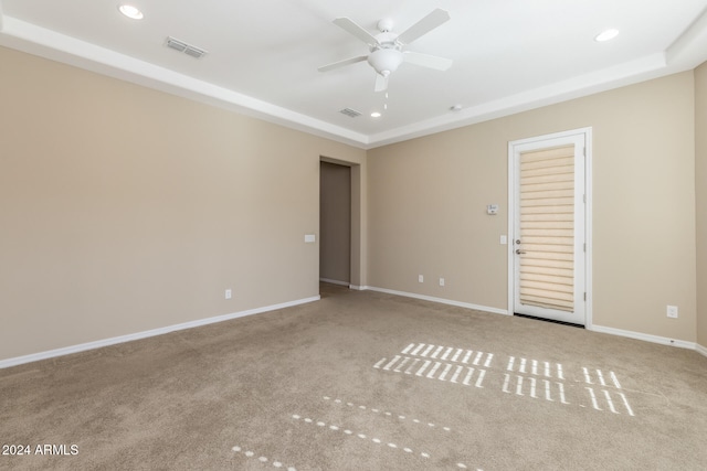 carpeted spare room with ceiling fan and a raised ceiling