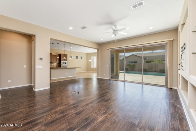 unfurnished living room featuring ceiling fan and dark wood-type flooring