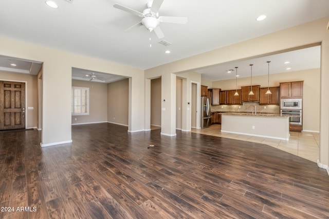 unfurnished living room with ceiling fan, dark wood-type flooring, and sink