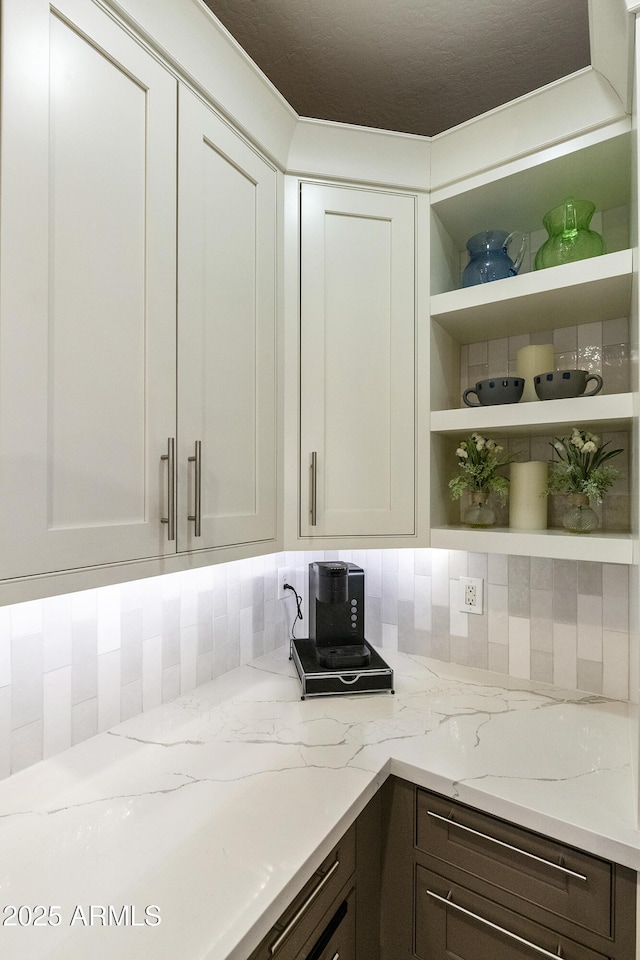 4524 E Narrowleaf Dr, Gilbert, AZ 85298 - kitchen featuring open shelves, light stone countertops, white cabinetry, dark brown cabinets, and backsplash