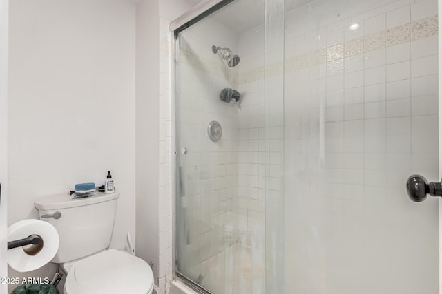 bathroom featuring a shower with shower door and toilet