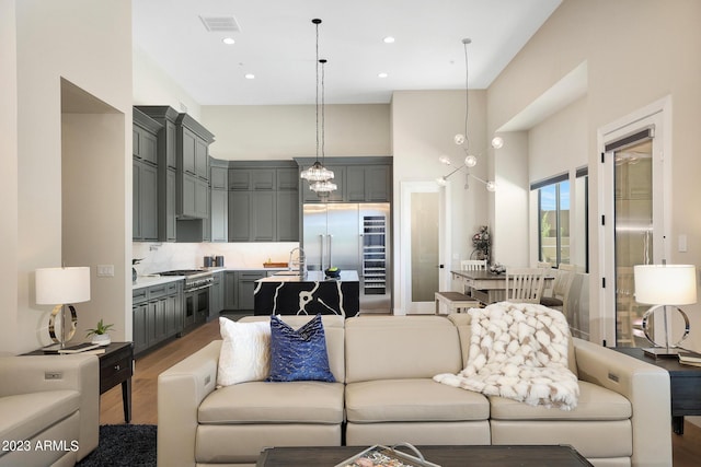 living area with a chandelier, recessed lighting, a towering ceiling, and wood finished floors