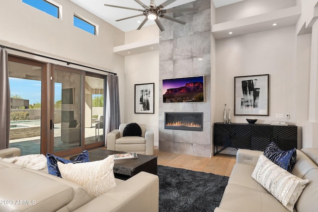 living room featuring a wealth of natural light, a tile fireplace, ceiling fan, and wood finished floors