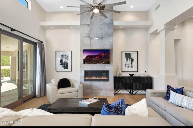 living area with a tile fireplace, wood finished floors, visible vents, and recessed lighting