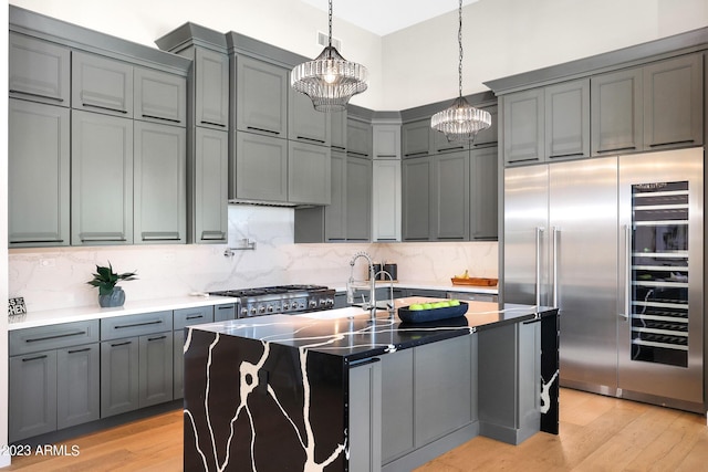 kitchen featuring range, light wood-style flooring, gray cabinets, and built in fridge