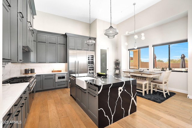 kitchen featuring light wood-type flooring, backsplash, a sink, and gray cabinetry