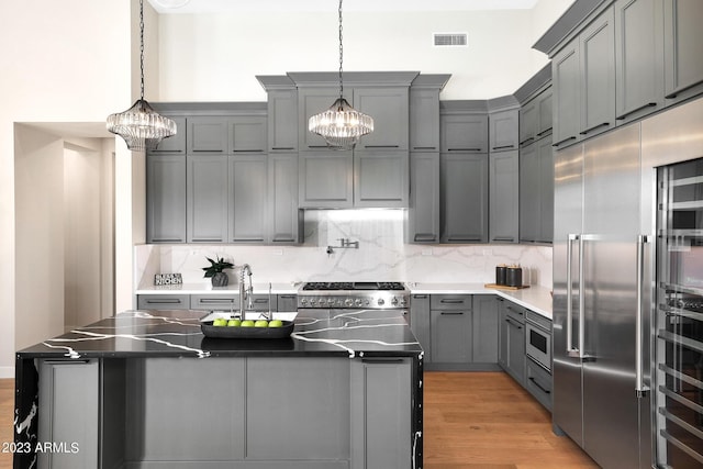 kitchen featuring built in appliances, gray cabinetry, visible vents, light wood-style floors, and tasteful backsplash