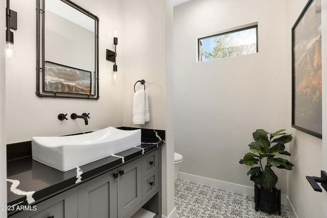 bathroom featuring baseboards, vanity, and toilet