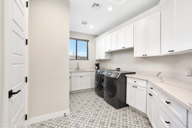 washroom with independent washer and dryer, cabinet space, a sink, and visible vents