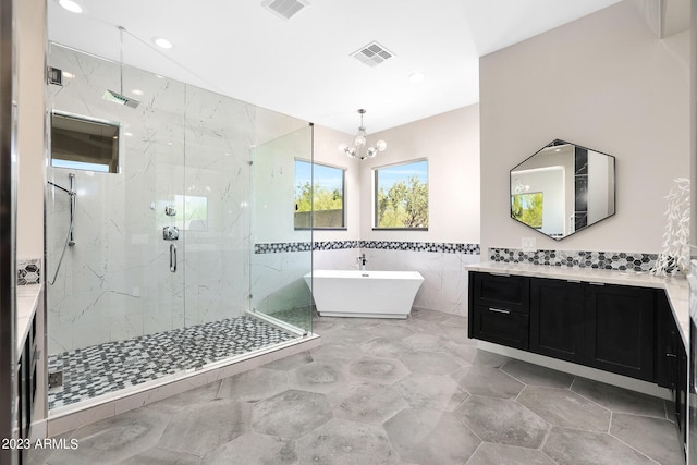 bathroom with a freestanding bath, a marble finish shower, visible vents, and tile walls