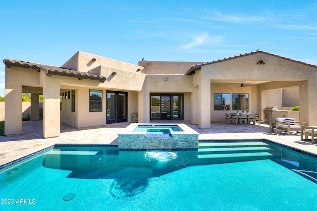 view of swimming pool featuring a pool with connected hot tub, an outdoor kitchen, outdoor dining space, a patio area, and ceiling fan