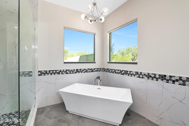 full bath with a shower, a freestanding tub, tile walls, and an inviting chandelier