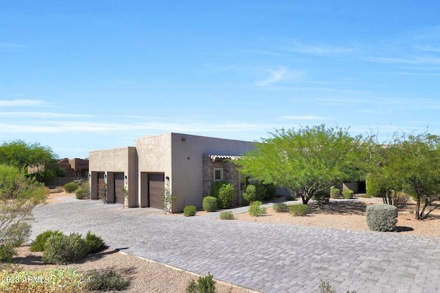 pueblo-style home with driveway, a garage, and stucco siding