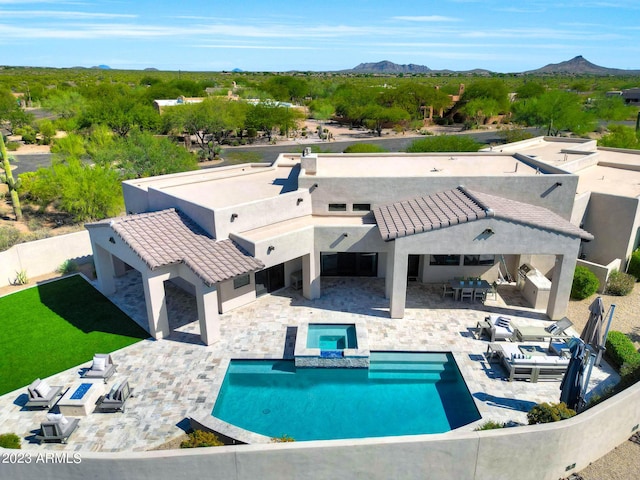 exterior space featuring a pool with connected hot tub, a patio area, a tile roof, and a mountain view