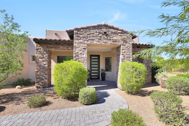 view of front facade with stone siding, a tiled roof, and stucco siding