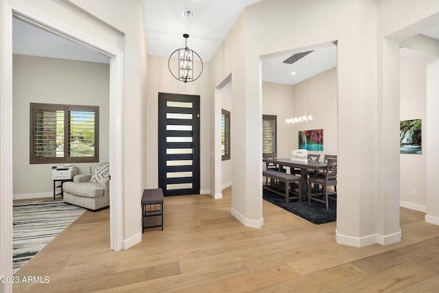 foyer entrance featuring a chandelier, wood finished floors, and visible vents