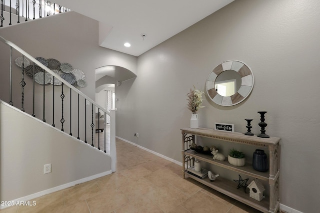 hall featuring baseboards, arched walkways, stairway, tile patterned flooring, and recessed lighting