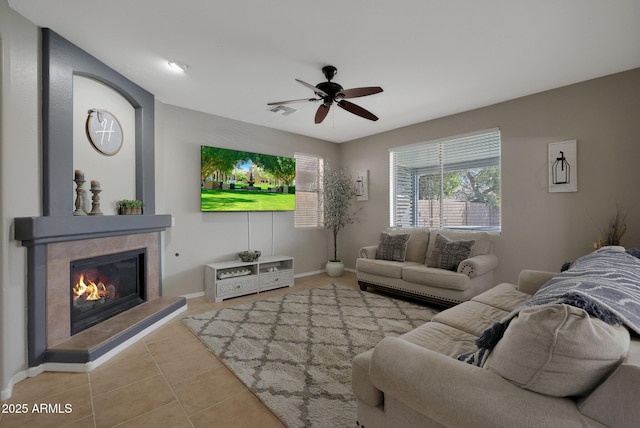 tiled living room with ceiling fan, a fireplace, visible vents, and baseboards