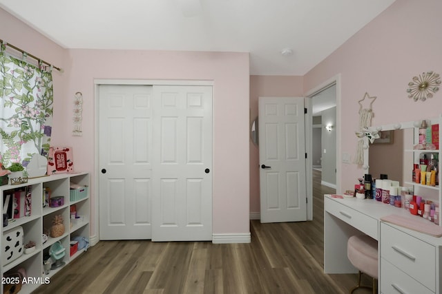 bedroom featuring dark wood-style flooring, a closet, and baseboards