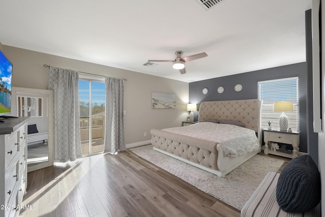 bedroom featuring access to outside, wood finished floors, visible vents, and baseboards