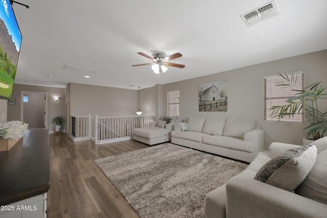 living area with ceiling fan, visible vents, and wood finished floors