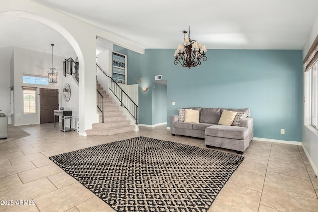 living room featuring a chandelier, tile patterned floors, stairs, high vaulted ceiling, and arched walkways