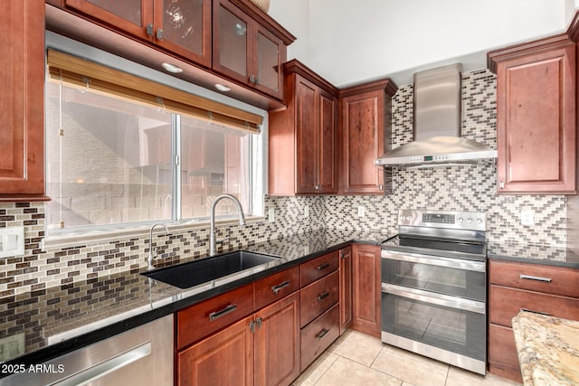 kitchen featuring wall chimney range hood, stainless steel appliances, a sink, and decorative backsplash